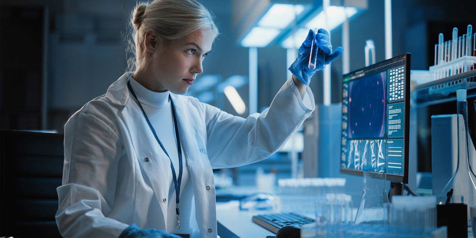 Standing employee in white coat with test tube behind screen